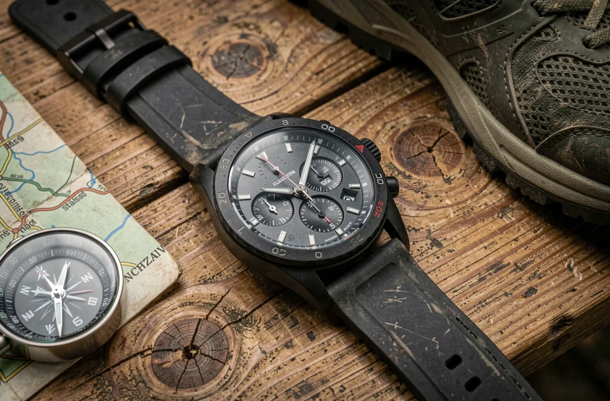 Gros plan d'un chronomètre sportif robuste posé sur une table en bois avec une carte de randonnée et une boussole